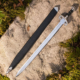 Éowyn sword prop replica full length on mossy stone in sunlit forest showing complete polished silver double fuller blade ornate antique brass swan-head D-guard crossguard brown leather ribbed grip and domed brass pommel – LOTR Shieldmaiden collectible