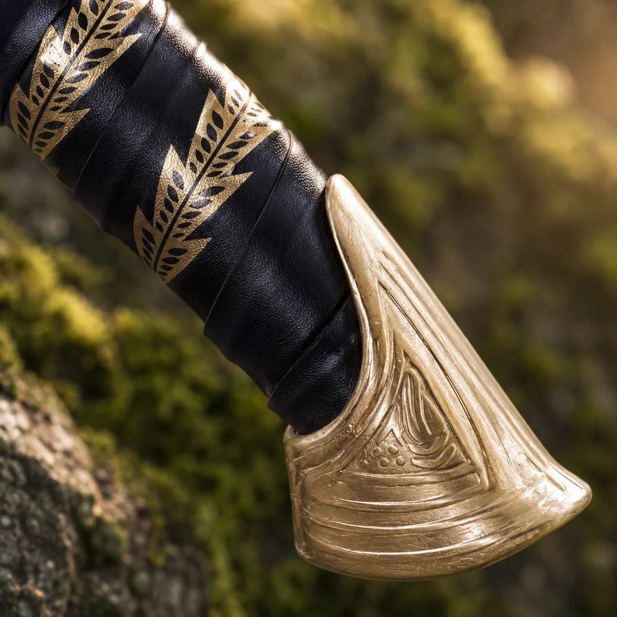 High Elven Warrior sword prop replica full length leaning on mossy log in sunlit fern forest showing complete curved polished silver Elvish blade black leather grip with gold leaf bands and gold triangular pommel – LOTR display collectible