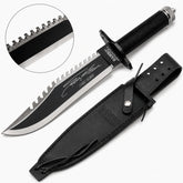 Rambo First Blood Part II Stallone Signature Edition knife prop replica full hero view on mossy log with black leather RAMBO FIRST BLOOD PART II embossed sheath showing black matte blade serrated saw-tooth spine Stallone facsimile signature 1188 10000 engraving RAMBO FIRST BLOOD PART II crossguard black diamond crosshatch knurled handle and knurled silver pommel cap – movie display collectible