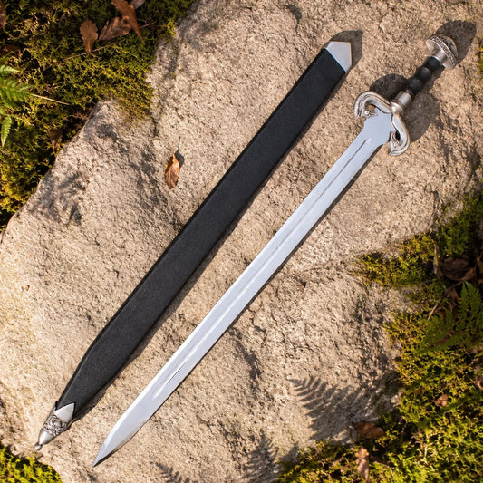 Éowyn sword prop replica full length on mossy stone in sunlit forest showing complete polished silver double fuller blade ornate antique brass swan-head D-guard crossguard brown leather ribbed grip and domed brass pommel – LOTR Shieldmaiden collectible