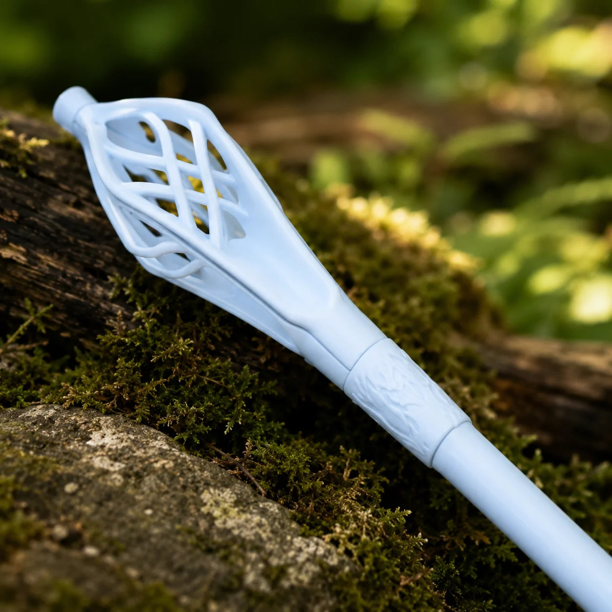 Gandalf the White staff prop replica full length on mossy rock in sunlit forest showing complete pale blue-white stainless steel shaft with ornate lattice cage topper and pointed tip – LOTR display collectible