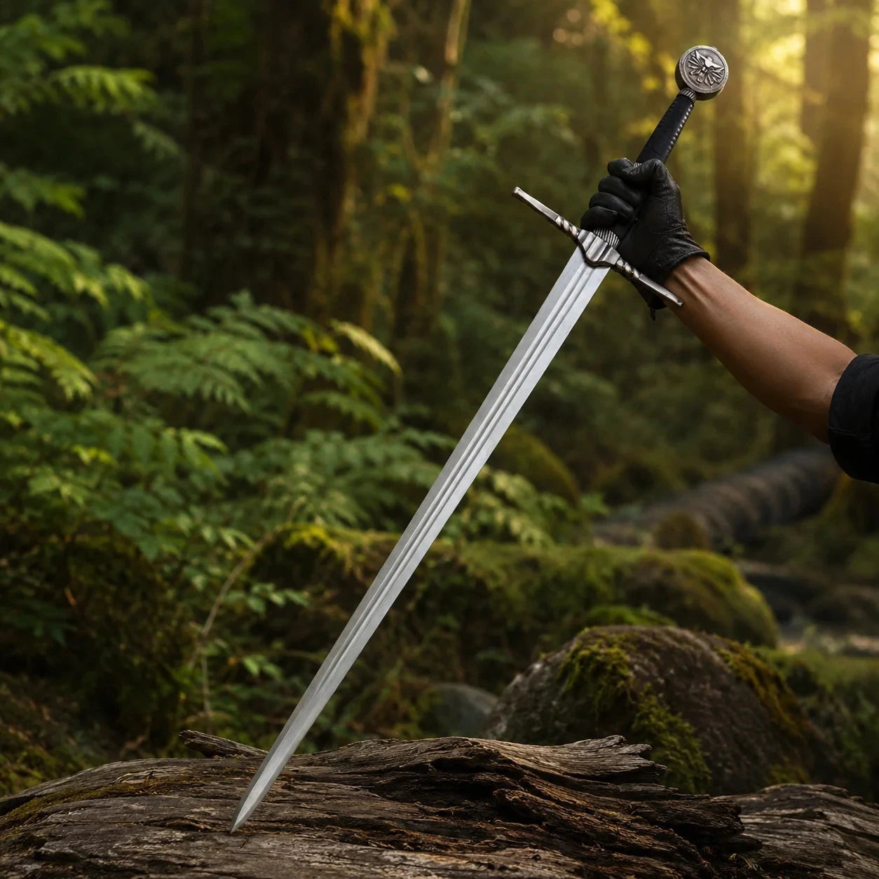 Geralt of Rivia Superior Wolven steel sword prop replica alternate full length diagonal view on mossy rock in sunlit forest showing complete polished silver blade with triple fuller grooves ornate silver angular crossguard black cord grip and School of the Wolf medallion pommel – Witcher wall display