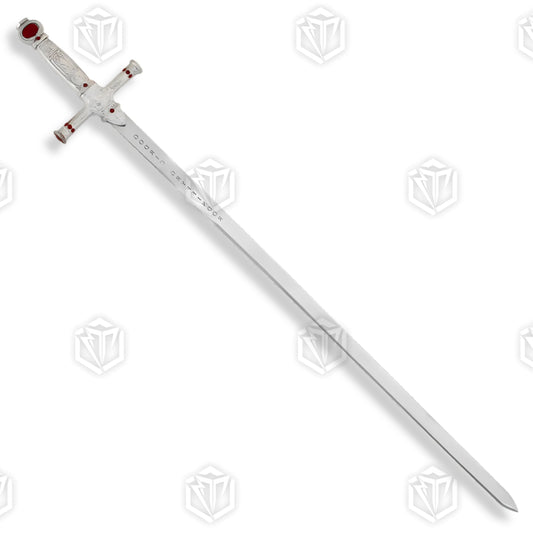 Godric Gryffindor sword prop replica full length diagonal on mossy rock in sunlit fern forest showing polished silver blade with Godric Gryffindor engraving ornate silver hilt and ruby red gemstones – Harry Potter display collectible