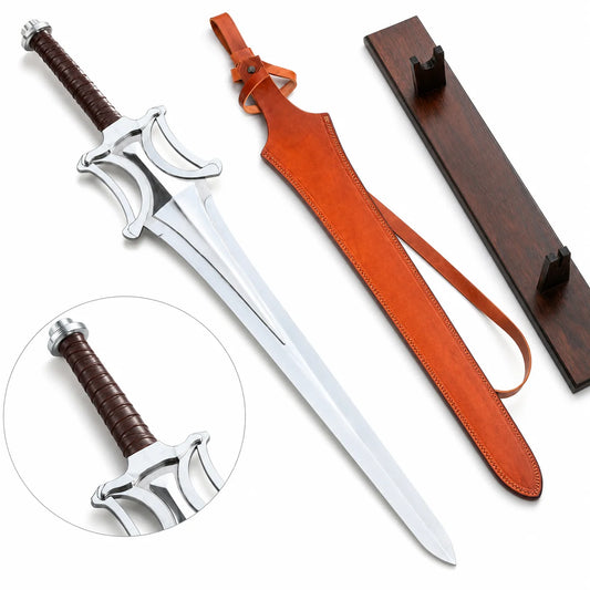 He-Man Power Sword prop replica full hero view on mossy rock with tan cognac leather scabbard belt loop and dark walnut wood display plaque notch holder showing silver chrome mirror-polish display finish blade double fuller groove open-work cross-guard four curved cutout arches and dark brown leather-wrapped handle – Masters of the Universe display collectible
