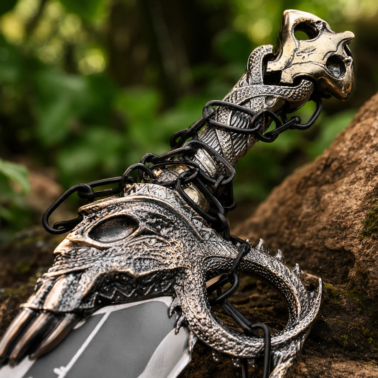 Close-up of Blades of Chaos handle showing ornate silver-bronze dragon skull pommel intricate scale-textured grip black chain links and detailed claw crossguard on God of War Norse prop replica collectible
