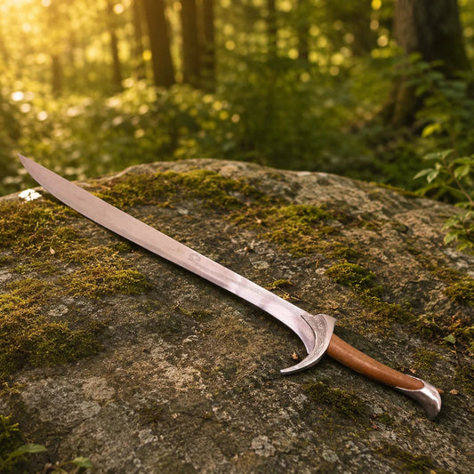 Orcrist sword prop replica close-up of ornate silver asymmetric crescent crossguard with Elvish floral scroll engravings and brown leather-wrapped grip with Elvish rune inscriptions in golden bokeh forest – Hobbit fan gift