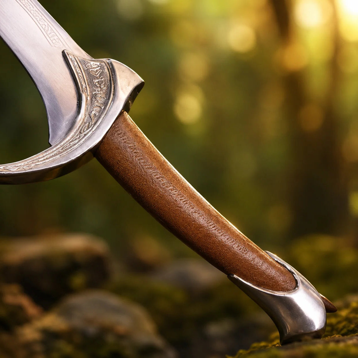 Orcrist sword prop replica close-up of polished silver curved Elvish blade tip with Elvish spiral scroll engraving and chain-link border fuller engraving in golden green bokeh forest – Tolkien Hobbit collectible