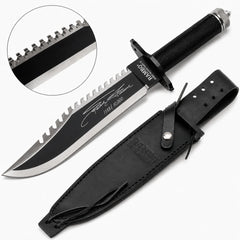 Rambo First Blood Part II Stallone Signature Edition knife prop replica full hero view on mossy log with black leather RAMBO FIRST BLOOD PART II embossed sheath showing black matte blade serrated saw-tooth spine Stallone facsimile signature 1188 10000 engraving RAMBO FIRST BLOOD PART II crossguard black diamond crosshatch knurled handle and knurled silver pommel cap – movie display collectible