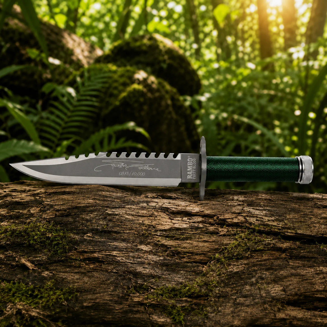 Rambo First Blood Stallone Signature Edition knife prop replica wide display view on mossy log showing full grey silver two-tone satin display finish blade profile with serrated saw-tooth spine Stallone signature engraving limited edition numbering green paracord-wrapped hollow handle and knurled silver pommel cap – Sylvester Stallone Rambo fan gift display piece