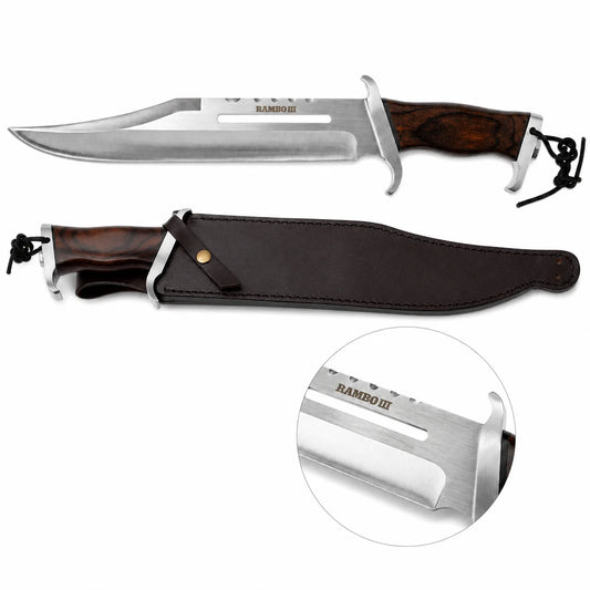 Rambo III Standard Edition knife prop replica held in gloved hand in sunlit green jungle forest showing silver satin display finish clip-point blade with RAMBO III engraving spine cut-outs dark walnut hardwood handle and silver double crossguard – movie display collectible